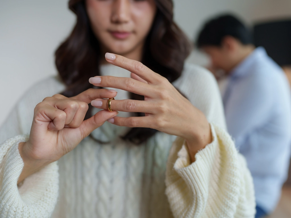 Sad woman holding her wedding ring indoors