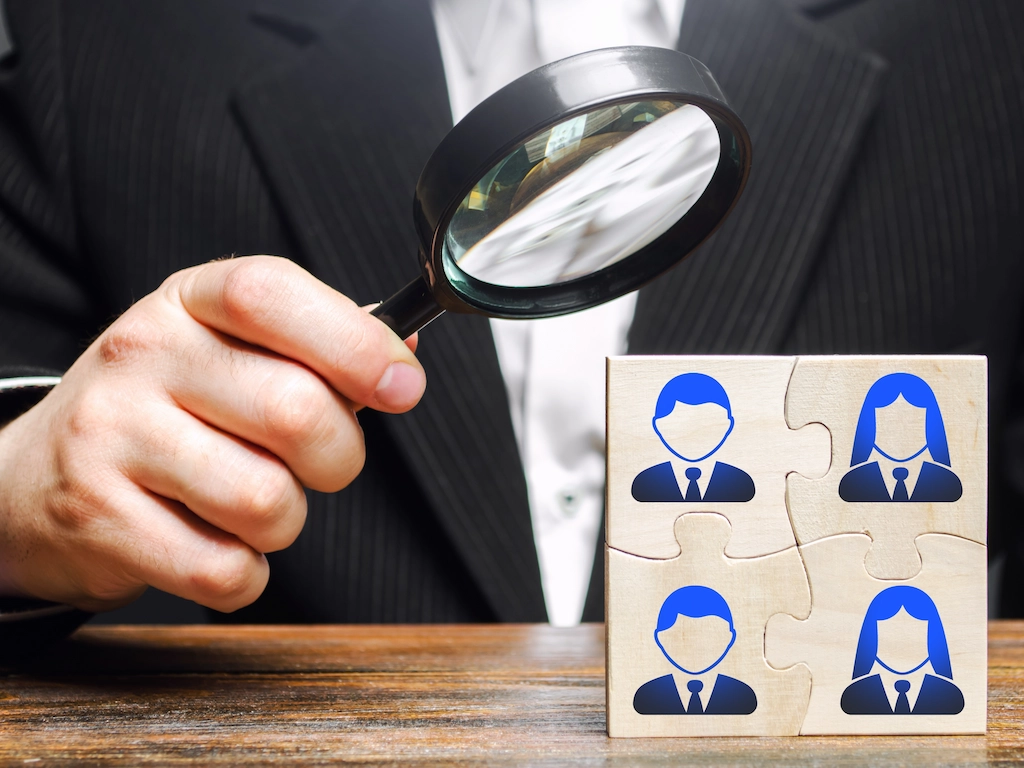 Man analyzing a puzzle with a magnifying glass on a desk