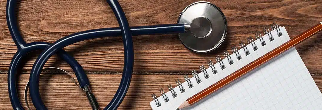 Stethoscope beside pen and paper