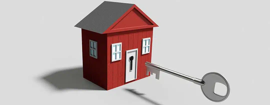 A toy house and a key pointing on the keyhole