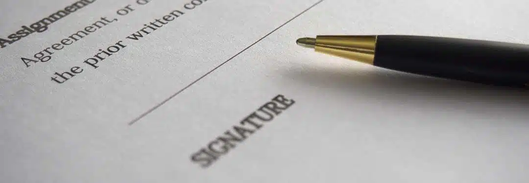 A pen at the signature line of a contract.