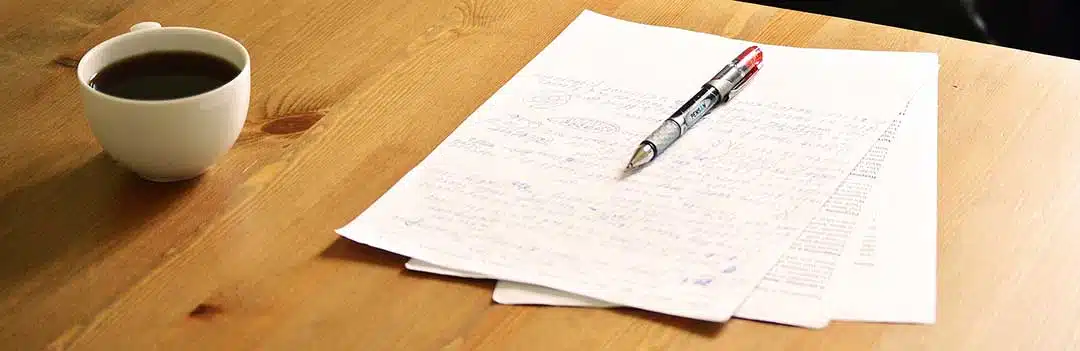 Pen on top of a letter beside a cup of coffee
