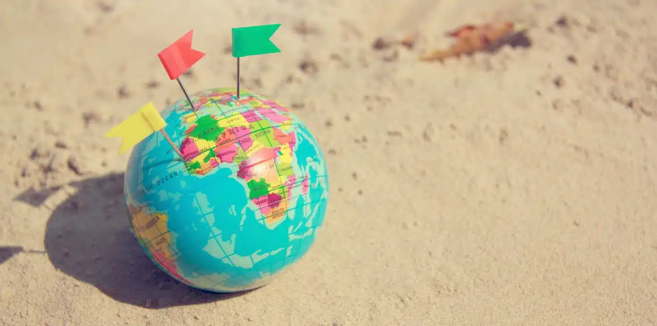 Alt text A World Globe sitting on sand with two mini flags pinned to it symbolizing that it is possible to file the petition for annulment in the Philippines with support from local counsel