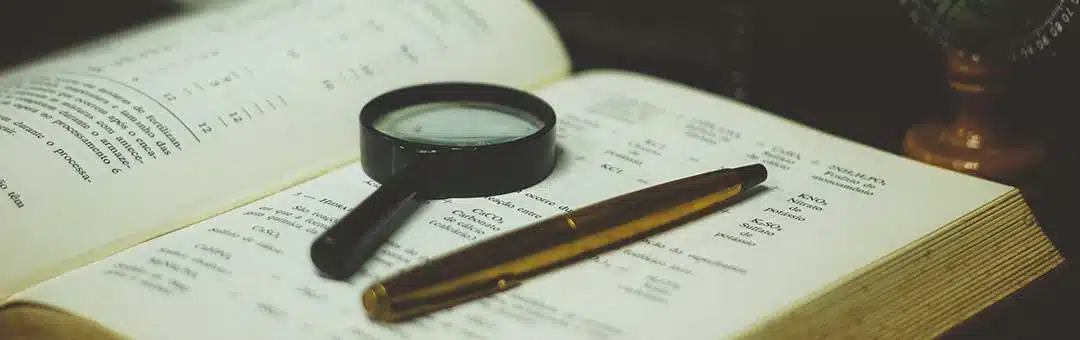 Magnifying glass and a pen on top of a book